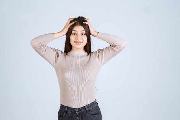 Girl in grey sweater holding her face and head. 