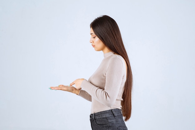 Girl in grey sweater looking to something at her hand. 