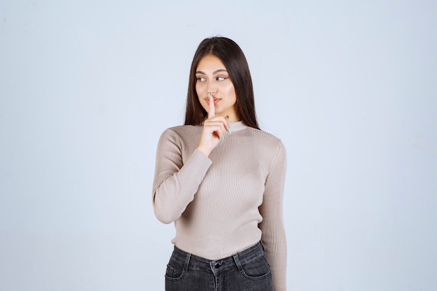 Girl in grey sweater pointing something above.