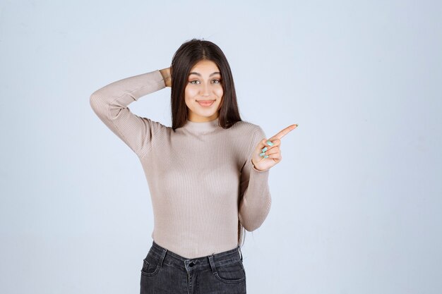 Girl in grey sweater pointing something above.