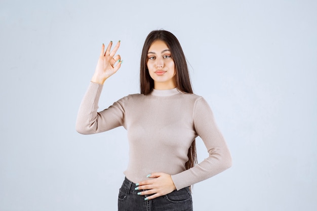 Girl in grey sweater showing circle ok sign. 