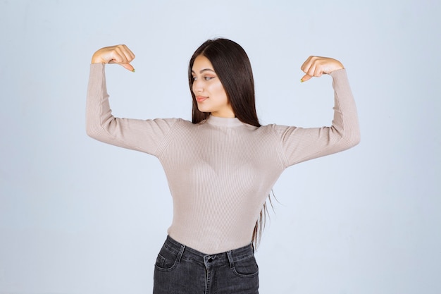 Free photo girl in grey sweater showing her fists and power.