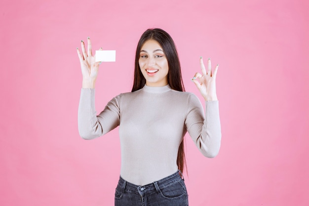 Girl in grey sweater showing her new business card making good hand sign