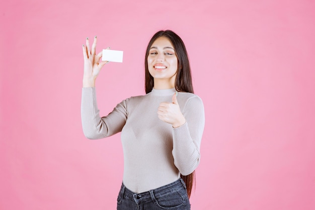 Girl in grey sweater showing her new business card making good hand sign