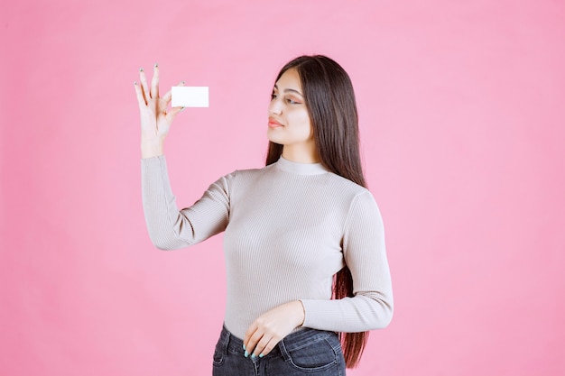 Девушка в сером свитере показывает и представляет свою визитную карточку