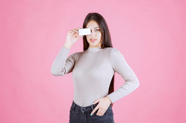 Girl in grey sweater showing and presenting her business card