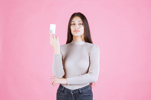 Девушка в сером свитере показывает и представляет свою визитную карточку