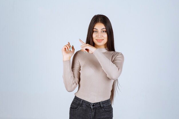 Girl in grey sweater showing something on the left.