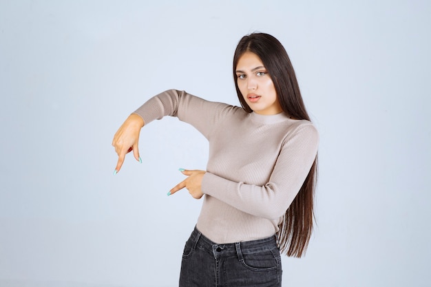 Foto gratuita ragazza in maglione grigio che mostra qualcosa a sinistra.