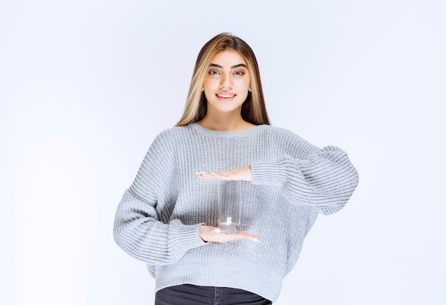 Girl in grey sweatshirt holding a glass of pure water .