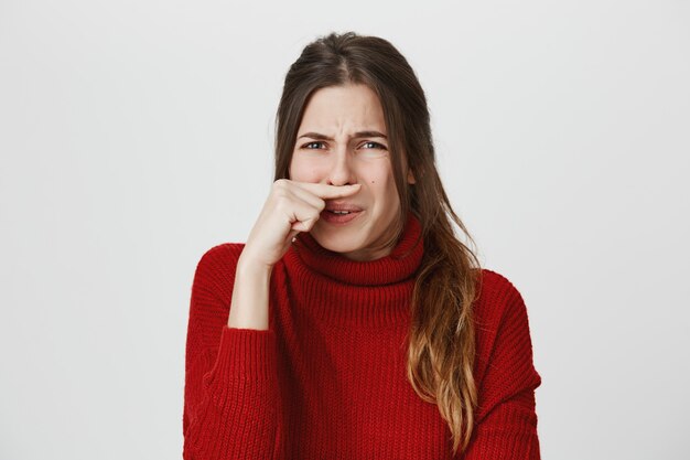 Girl grimacing, close nose from disgusting smell