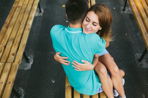 Free photo girl and guy sitting on bench hugging