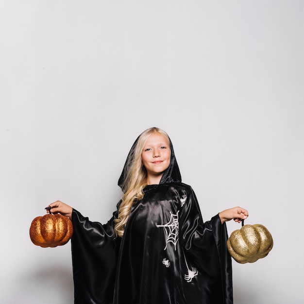 Free photo girl in halloween costume holding pumpkins