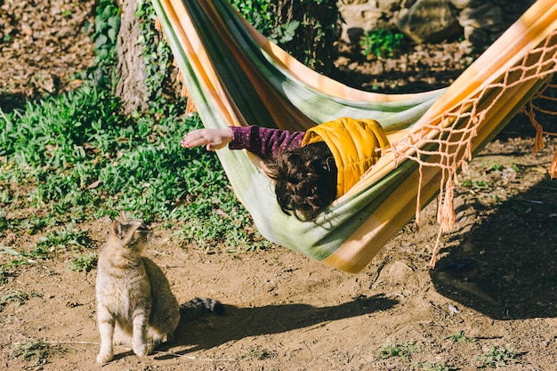 Girl in hammock playing with cat
