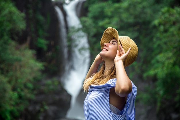girl in hat looking at the waterfall