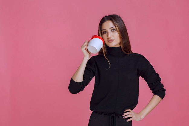 Ragazza che mangia una tazza di caffè durante la pausa caffè.