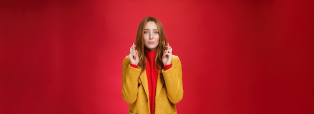 La ragazza che ha fede che tutto vada bene incrocia le dita per buona fortuna mentre supplica esprimendo un desiderio