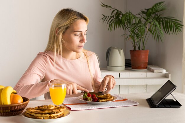 Girl having waffles watching tablet