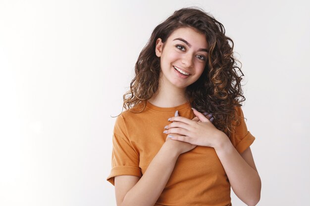 Girl heart melting pleasant warm confession. Charming young armenian woman holding hands chest sighing romantic smiling in love standing white background look passionate grateful