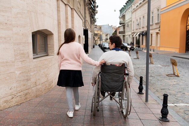 Girl helping disabled man traveling in the city