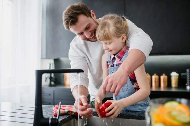 Девочка помогает отцу вымыть овощи
