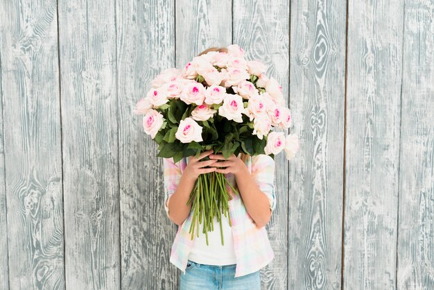 Girl hiding face by bouquet of roses