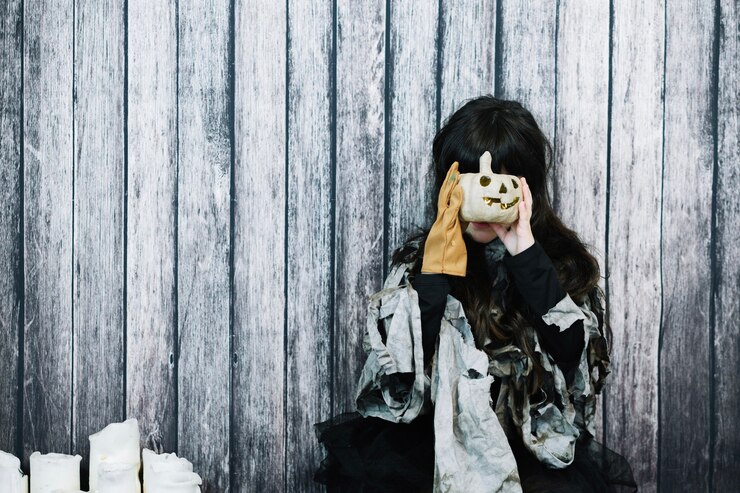 Free Photo girl hiding her face behind pumpkin