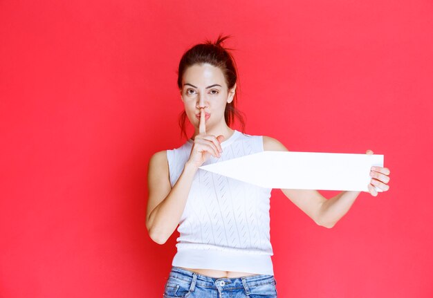 Girl holding an arrow pointing at the west and whispering the address. 