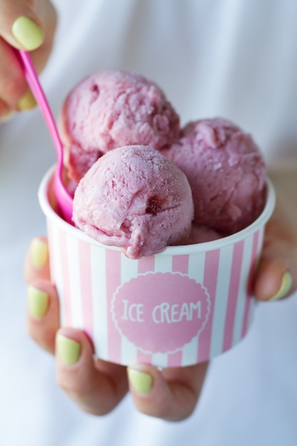 Girl holding beautiful appetizing ice cream cup with many ice cream scoops. Closeup.