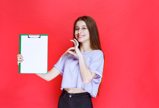 Girl holding a blank reporting sheet and showing enjoyment sign. 