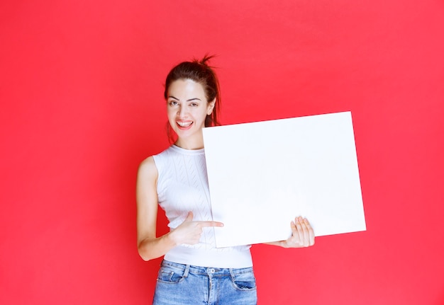 Girl holding a blank square ideaboard for brainstorming. 