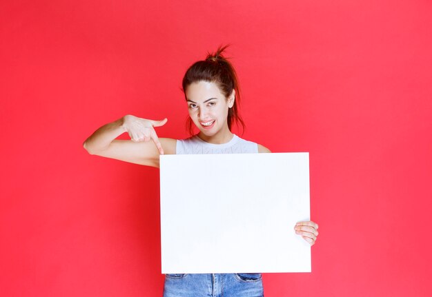 Girl holding a blank square ideaboard for brainstorming. 