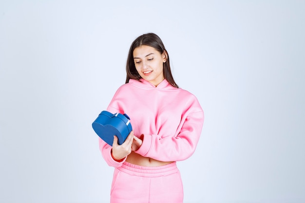 Girl holding a blue gift box and looking at it. 