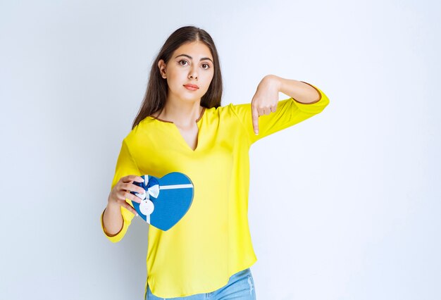 Girl holding a blue heart shape gift box and calling someone to present it