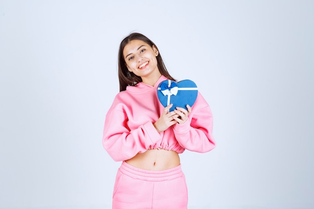 Girl holding a blue heart shape gift box and demonstrating it. 