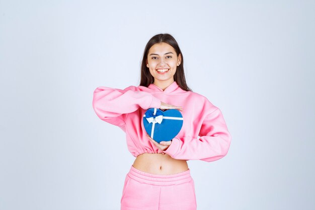 Girl holding a blue heart shape gift box and demonstrating it