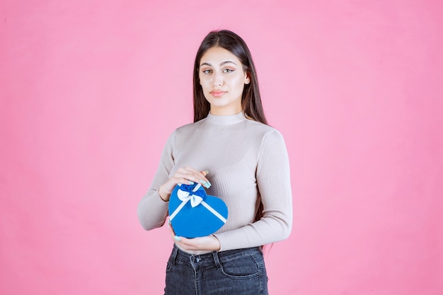 Girl holding a blue heart shaped giftbox and demonstrating it