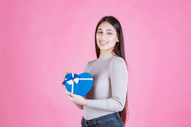 Girl holding a blue heart shaped giftbox and demonstrating it