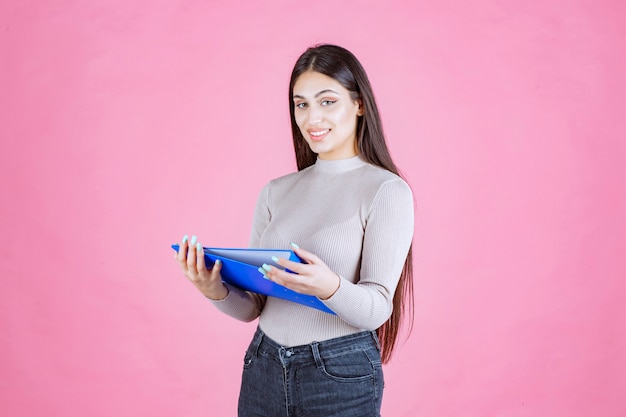 Girl holding a blue project folder and looks successful and happy