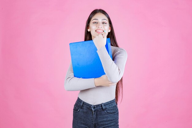 Girl holding a blue project folder and looks successful and happy