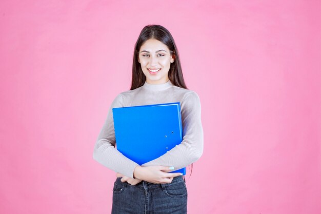 Girl holding a blue project folder and looks successful and happy