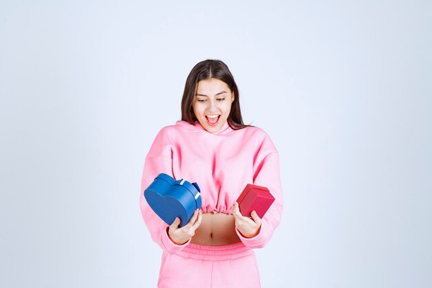 Girl holding blue and red gift boxes in both hands. 