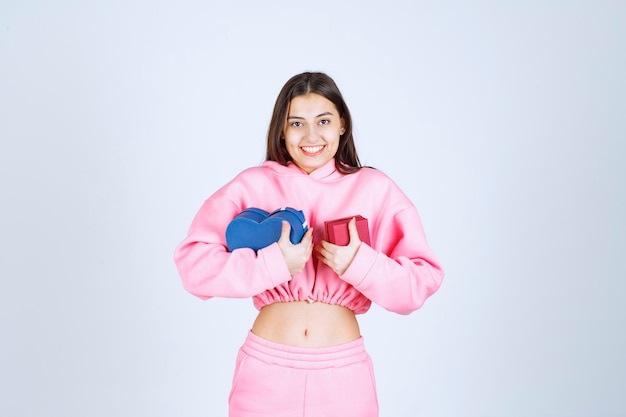 Girl holding blue and red gift boxes in both hands. 