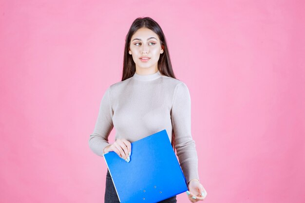 Girl holding a blue report folder and looks tired