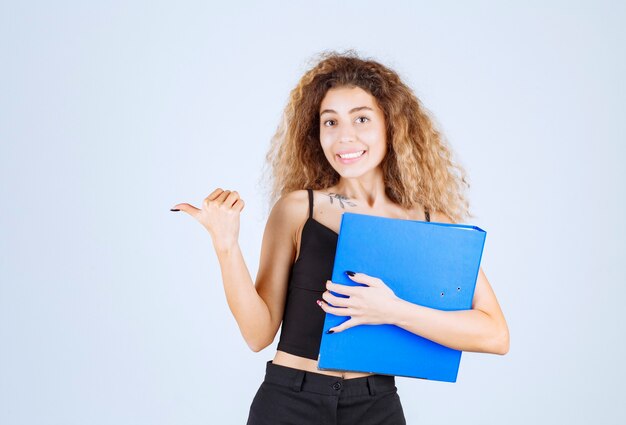 Girl holding a blue task folder and pointing at her friend. 