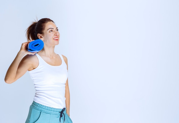 Girl holding a blur rolled up yoga matte. 