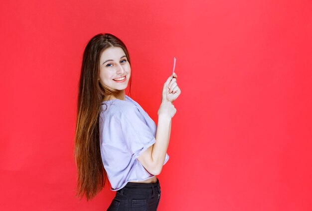 Girl holding a business card and looks happy. 