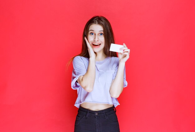 Girl holding a business card and looks surprized and excited. 