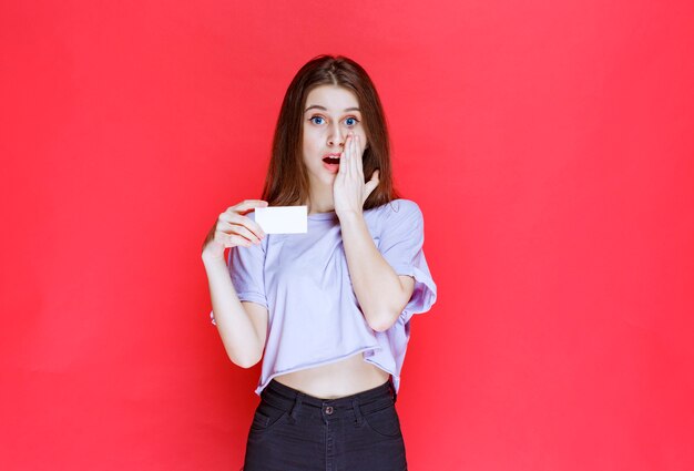 Girl holding a business card and looks surprized and excited. 