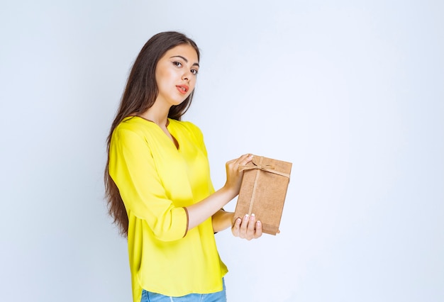 Girl holding a cardboard gift box and feeling positive.